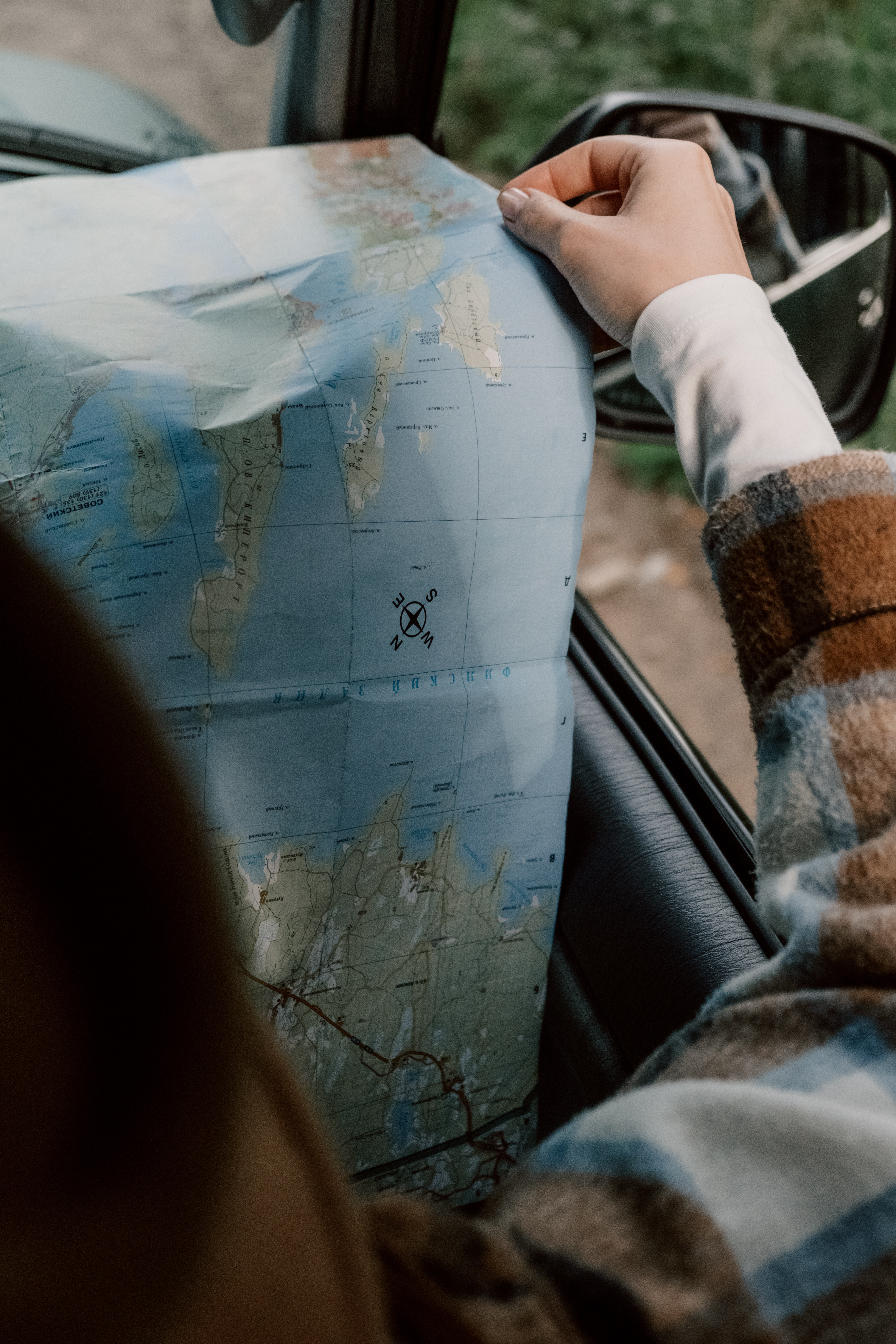 Close up of a hand holding the edge of map sitting in a car.