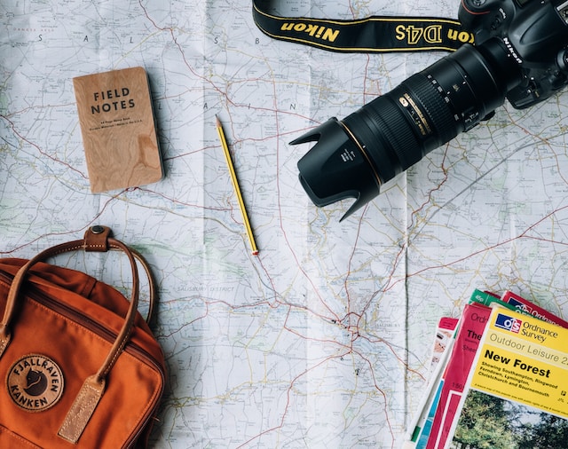 A physical map including a digital camera, pencil, bag, and some route-planning books