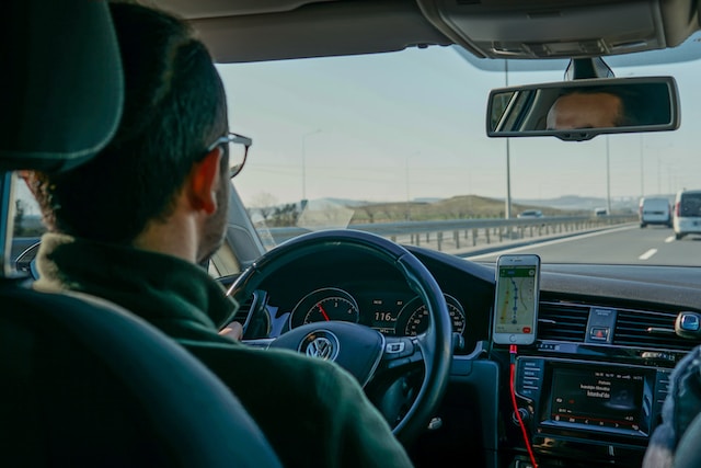 A driver utilizing a navigation app while traveling in his car.