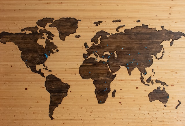 A wooden map of the world with pins.