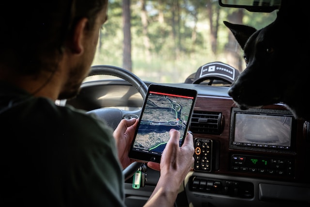 A man in his car using a navigation app on his iPad to find the fastest way home.