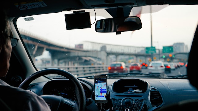 A driver navigating a high-traffic road via a navigation app on his phone to reach his destination as fast as possible.