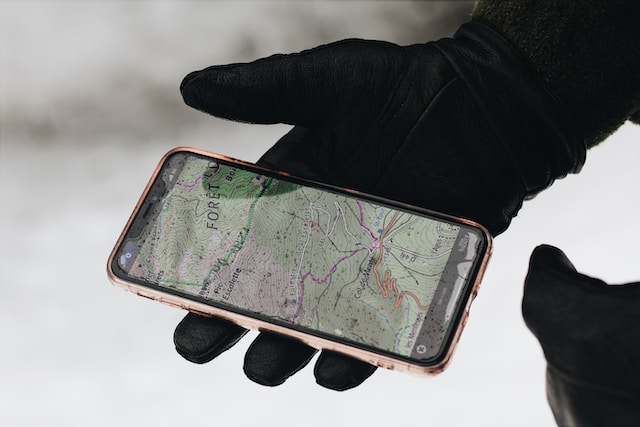 A person holding a smartphone with a map displayed on the screen.