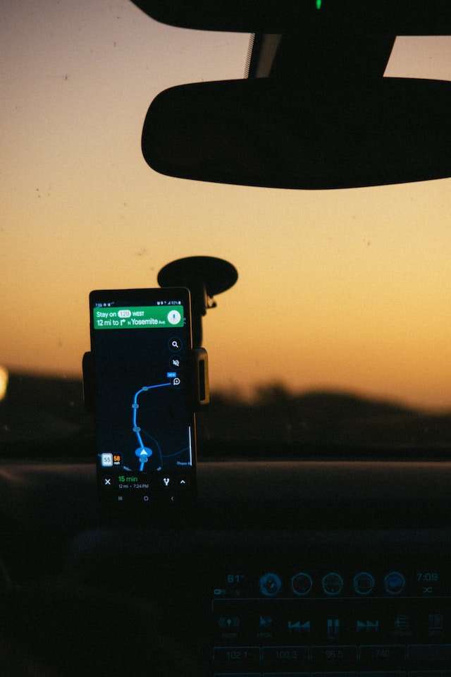 A smartphone displaying Google Maps stops on a holder inside a car.