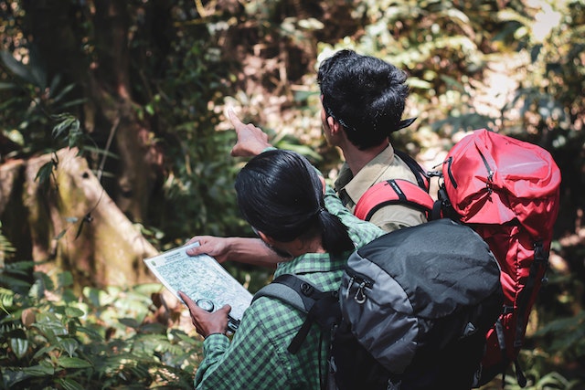 A couple utilizing a physical map to navigate a hiking trail.