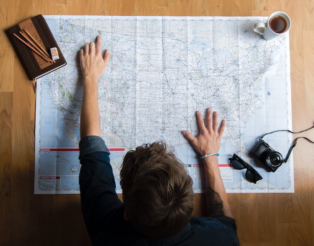 A man considering the map of the US with cities to help his navigation.