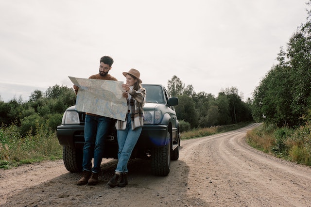 A couple on the road planning their trip on a physical map.