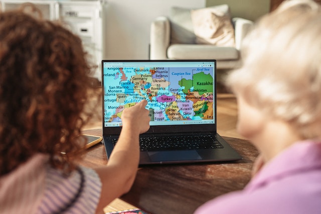 A mother and her daughter viewing different countries via a map on a PC.
