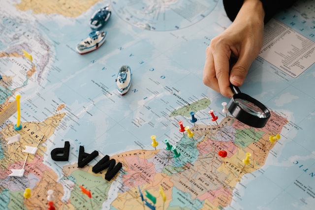 A user examining geographic regions on a well-detailed map with a reading lens.