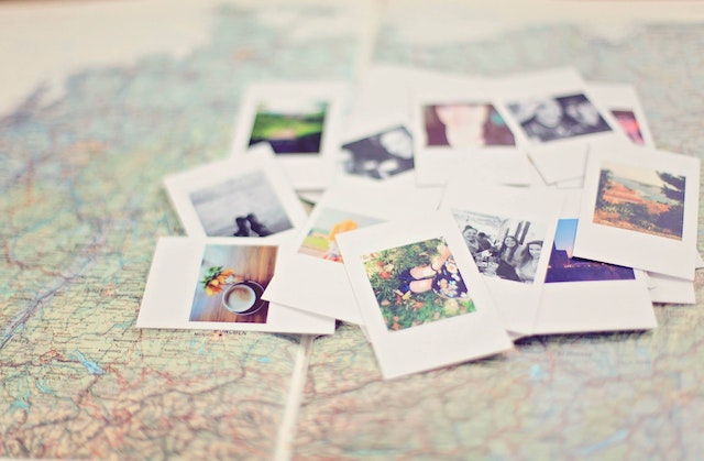 Close-up of small photos laying on top of an open map book.
