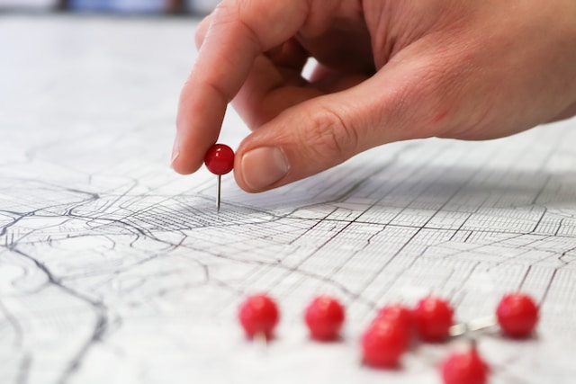A person placing pins on a physical map to calculate distances between two points.