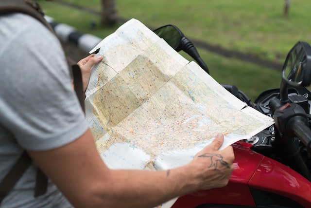 A driver checking a physical map of an area for possible routes before starting his journey. 