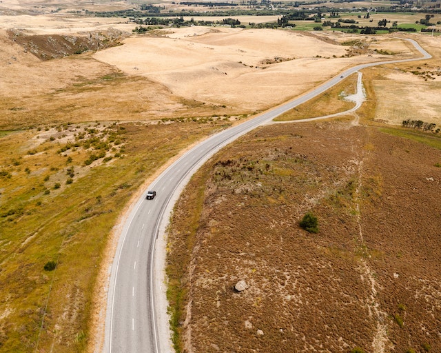 An aerial shot of a car embarking on a long-distance road trip.
