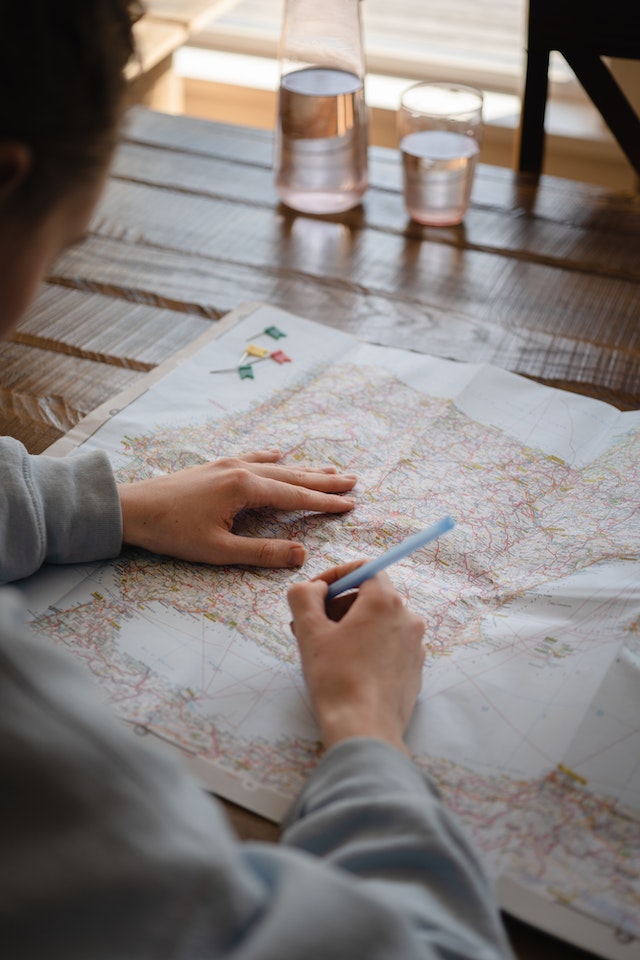 Person using a pen to plot latitude and longitude points on a paper map.