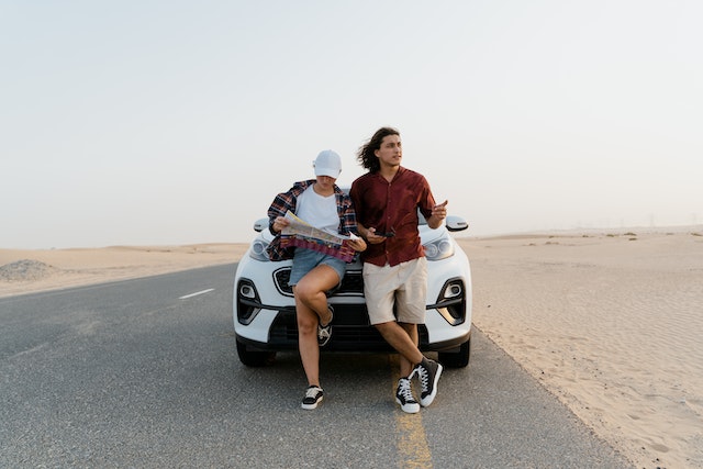 A couple on the road utilizing a physical map to check out their next destination. 