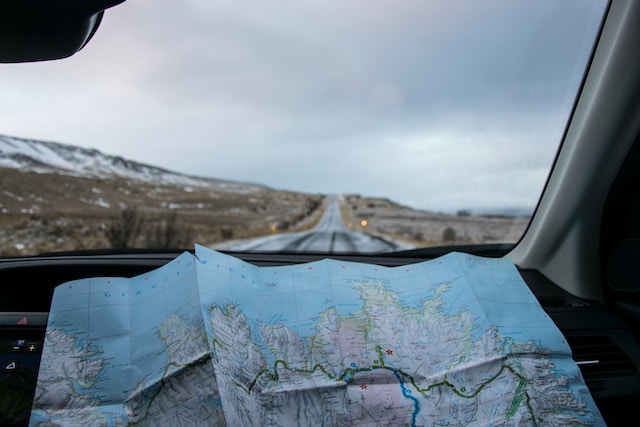 A physical map on a car’s dashboard being used to navigate newer destinations. 