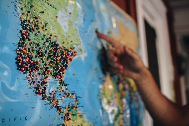 A user using push pins on a physical map to highlight the population distribution in the US. 