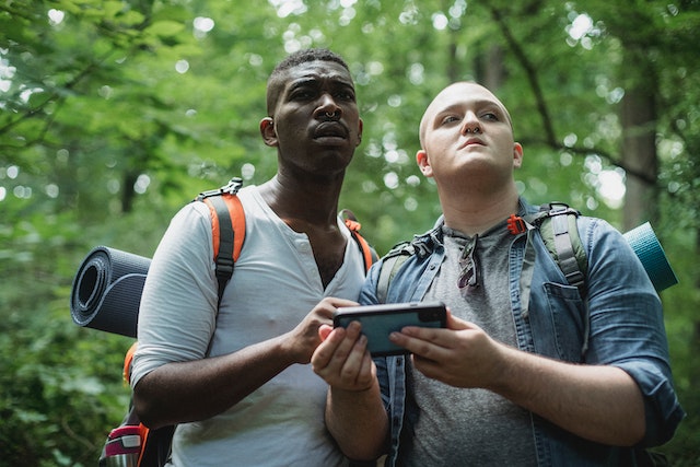 Two guys checking out a navigation app along a route in the woods.