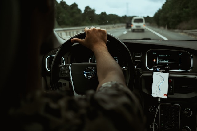 A driver using a map app on his mobile phone to find the best route to his destination.
