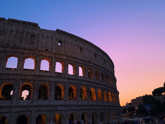 Beautiful sunset view of the Roman Colesseum next to city streets.